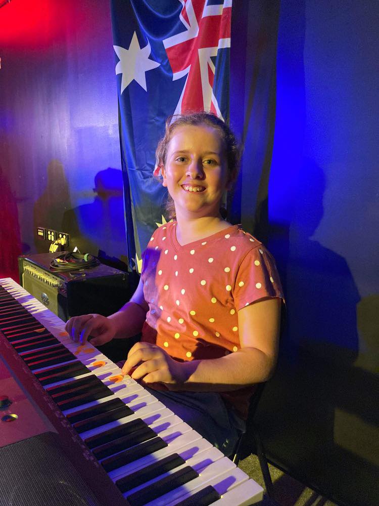 Young girl playing a keyboard and smiling