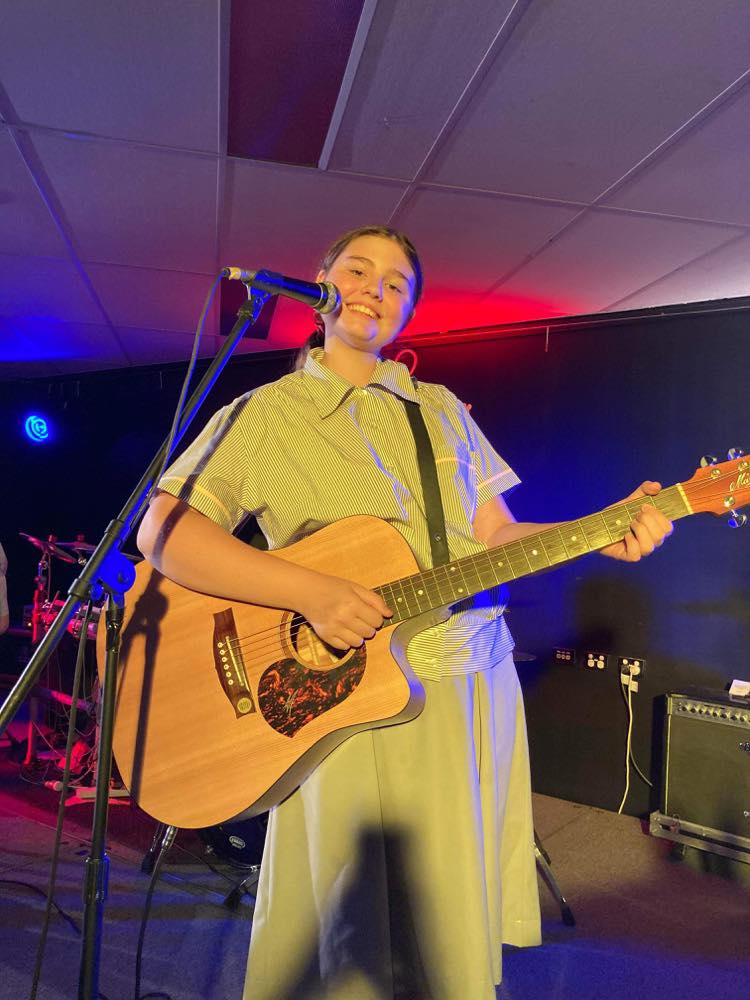 Young girl playing the guitar and smiling